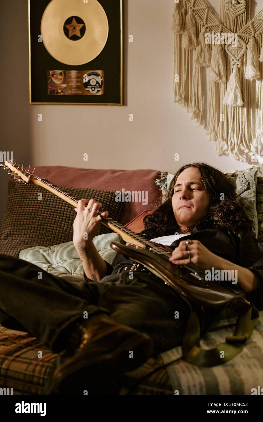 Uomo adulto che prova la chitarra rock a casa per la promozione musicale Foto Stock