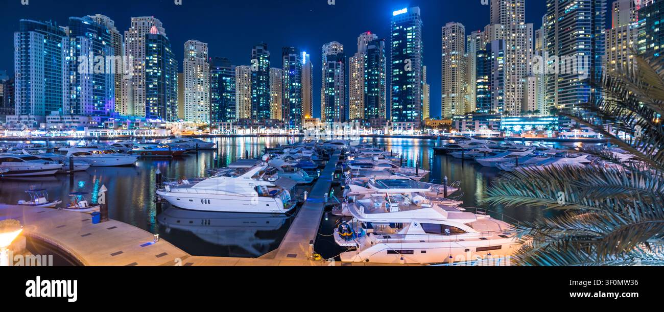 Gli yacht di lusso allineano i moli illuminati della Dubai Marina, uno dei più grandi porti artificiali del mondo. Foto Stock