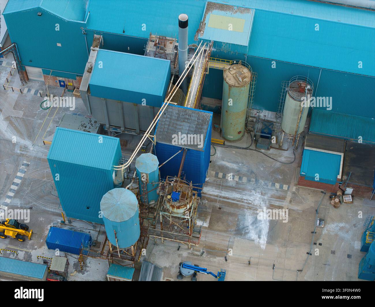 Vista aerea della struttura industriale Saint Gobain Formula con edifici rivestiti in metallo blu, grandi silo di stoccaggio e apparecchiature di lavorazione industriale i Foto Stock