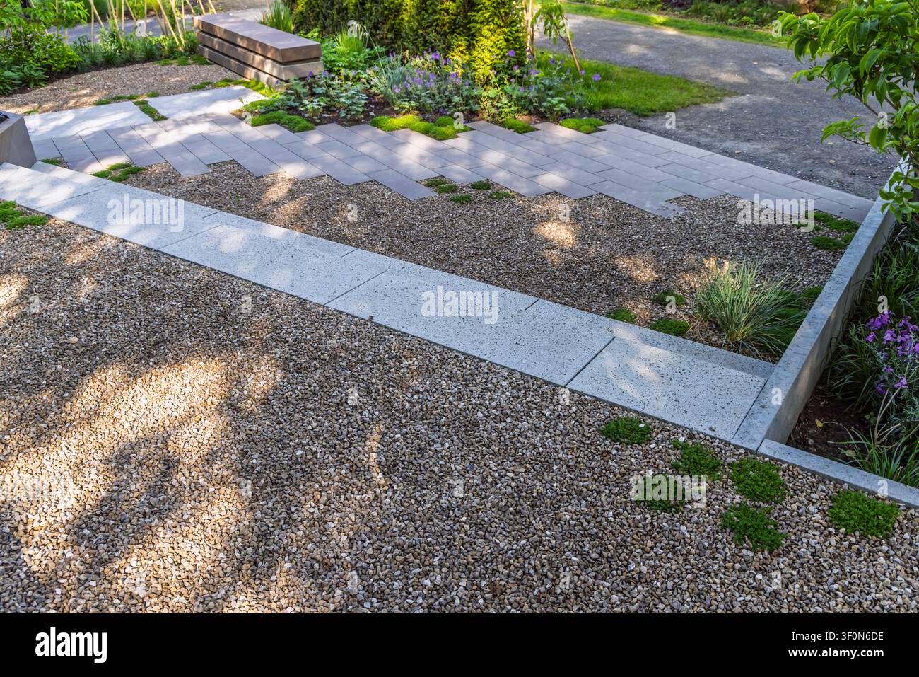 Design moderno del giardino con sentieri di ghiaia e pietre di pavimentazione geometriche Foto Stock