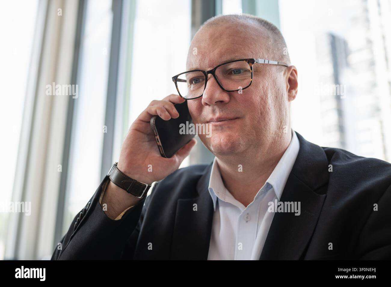 Ritratto di un uomo d'affari caucasico sicuro di sé che parla al telefono in un ufficio moderno. Comunicazione aziendale, negoziazione e networking professionale co Foto Stock