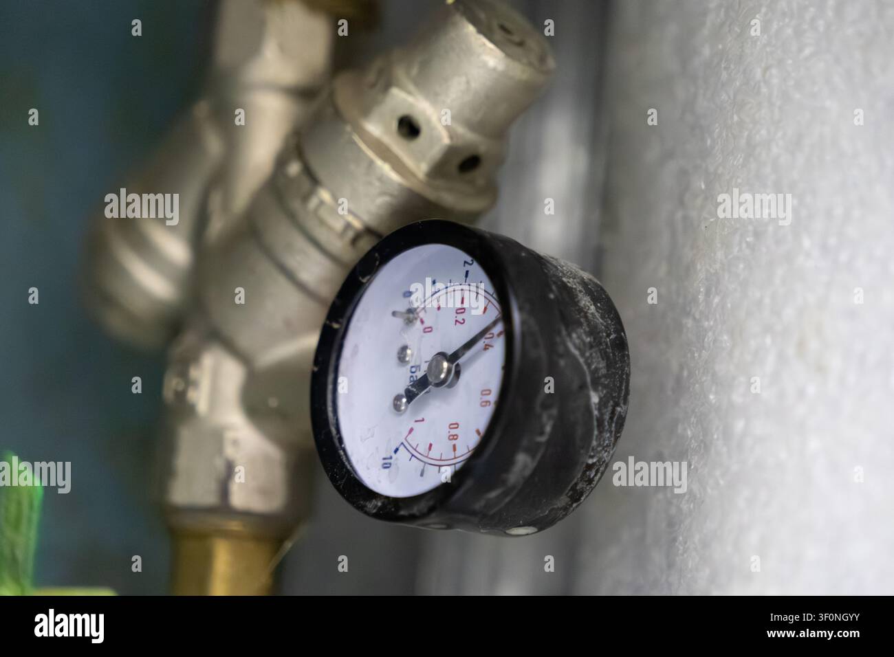 Una vista ravvicinata di un misuratore barometrico su un raccordo metallico per riparazioni idrauliche, che mostra un controllo preciso della tensione del liquido nei sistemi climatici degli edifici moderni Foto Stock
