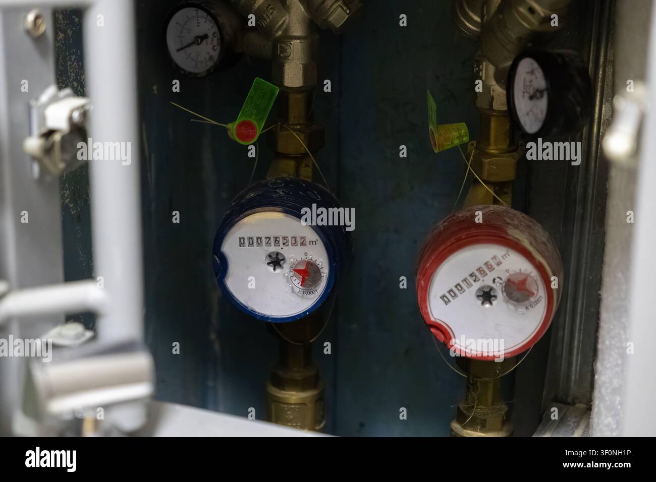 Dispositivi professionali per la misurazione del flusso dell'acqua attaccati a tubi metallici all'interno di un armadio di servizio, che riflettono il monitoraggio moderno dell'utilizzo dell'acqua e la manutenzione degli edifici Foto Stock