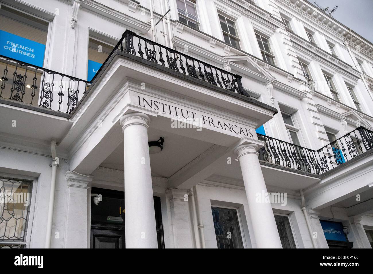 La facciata bianca dell'Institut Francais du Royaume-Uni mostra l'ingresso scolpito dell'Institut Francais, balconi in ferro nero e cartelli blu delle finestre pronti Foto Stock