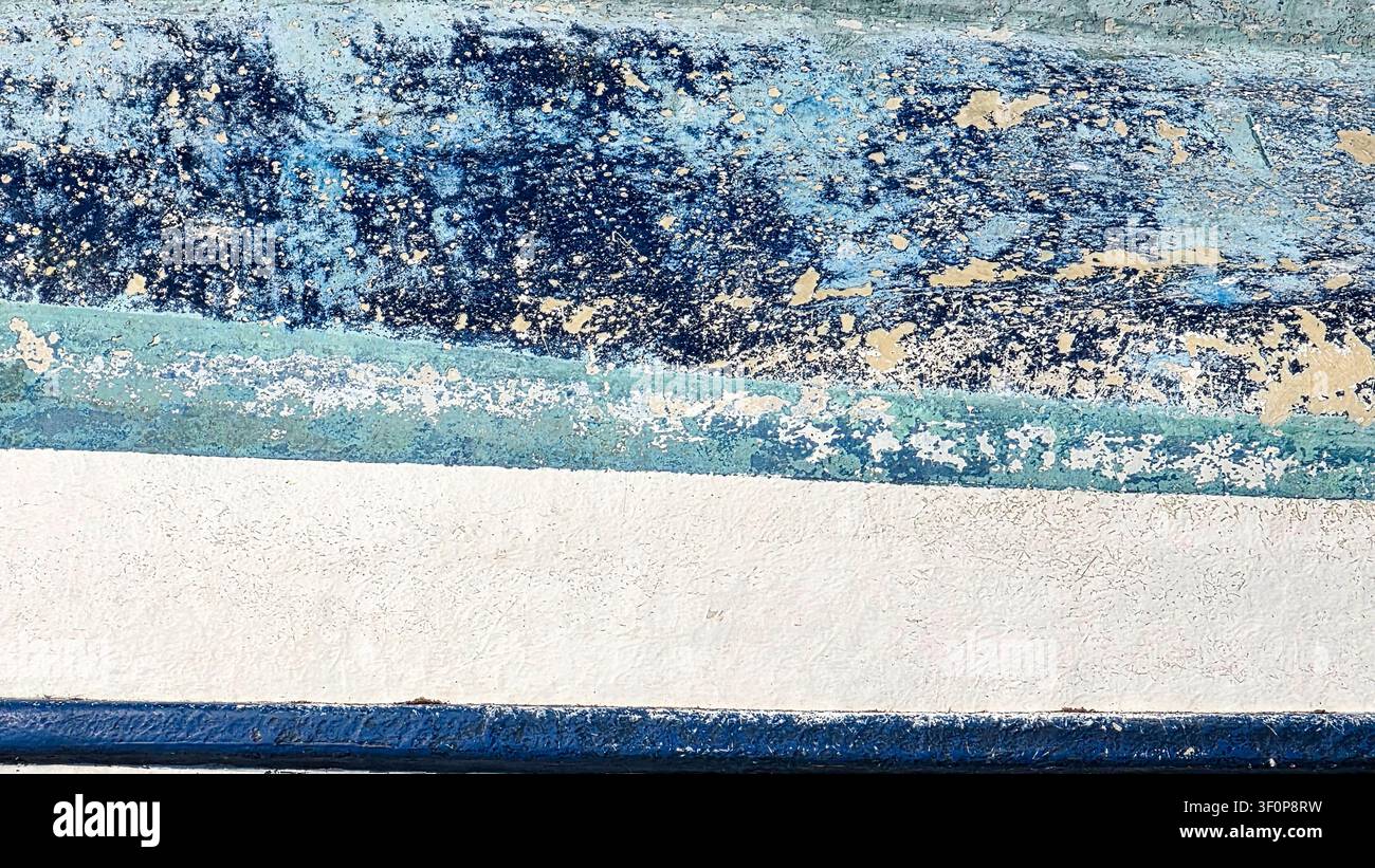 Immagine in primo piano di un muro ruvido con vernice blu e bianca scrostata, che mostra superfici consumate e invecchiate con strati di colori e motivi ruvidi Foto Stock