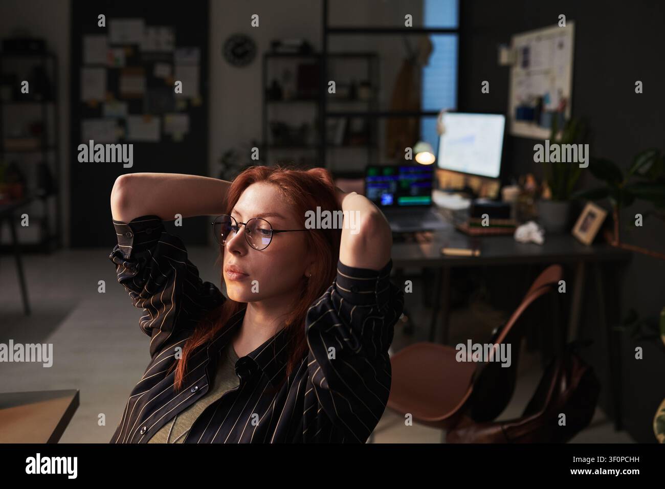 Donna adulta che si rilassa dopo il lavoro in ufficio durante il turno serale Foto Stock