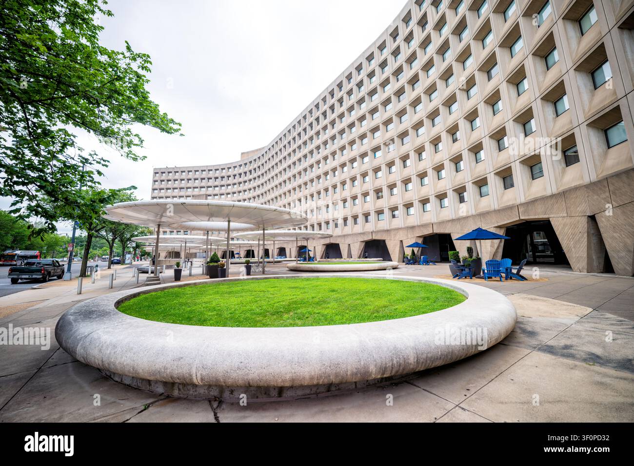 Edificio Robert C Weaver a Washington DC | WASHINGTON D.C., Stati Uniti — La facciata curva in cemento dell’edificio Robert C. Weaver si snoda lungo la Seventh Street, con le sue finestre incastonate che formano una delle facciate brutaliste più riconoscibili di Washington. Marcel Breuer progettò la sede del 1968 per il Dipartimento degli Alloggi e dello Sviluppo Urbano utilizzando pannelli precolati con faccia concava disposti in una griglia ripetitiva. Le coperture a forma di piattino e i prati circolari davanti all’ingresso furono aggiunti in seguito per mitigare l’aspetto famosamente austero dell’edificio. Foto Stock