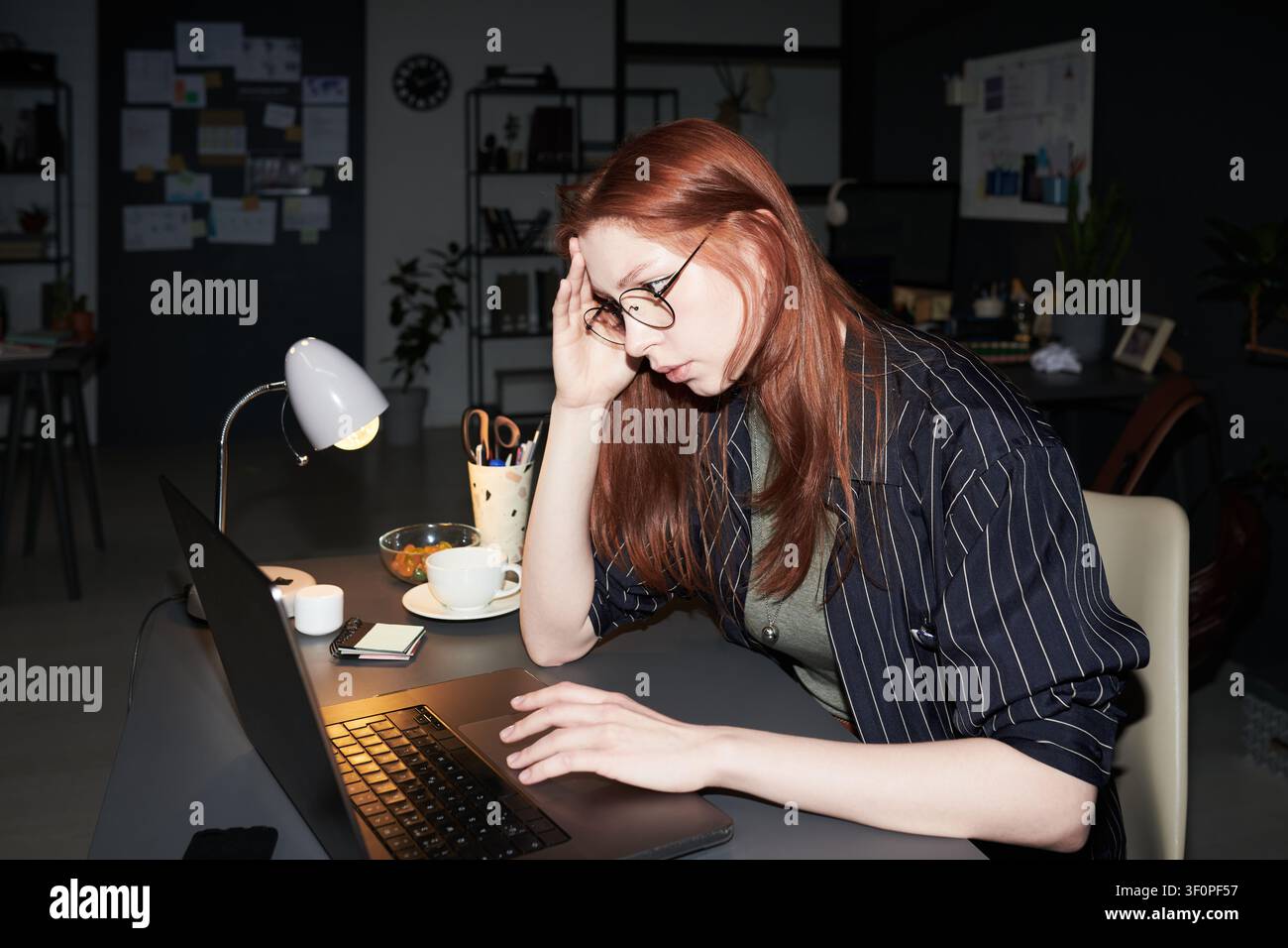 Donna adulta che lavora fino a tardi sul laptop e vive un burnout Foto Stock