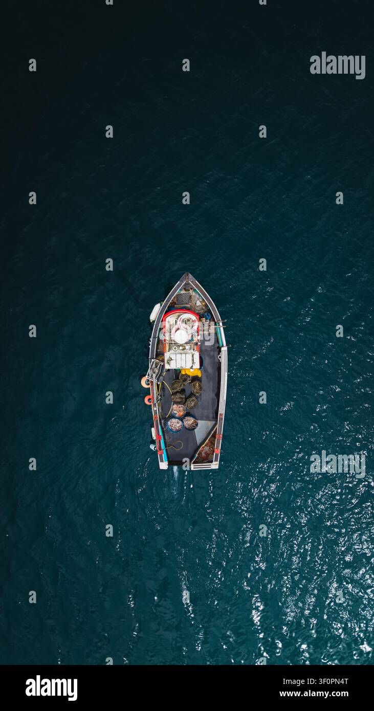 Vista aerea direttamente sopra un piccolo tradizionale peschereccio cornico e un pescatore in acque aperte che pesca granchi, aragoste e un aumento di polpi Foto Stock