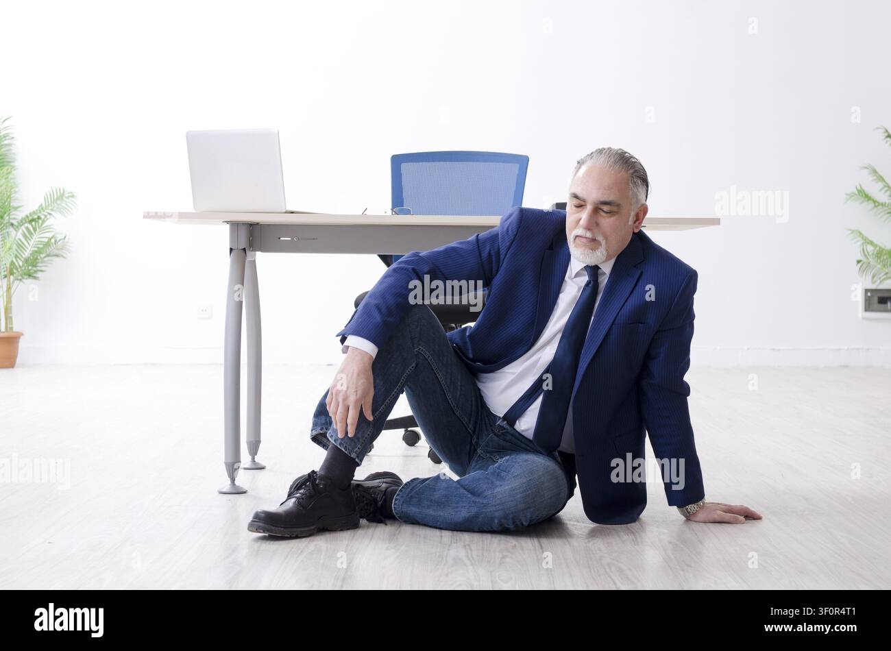 Imprenditore invecchiato facendo esercizi yoga in ufficio Foto Stock