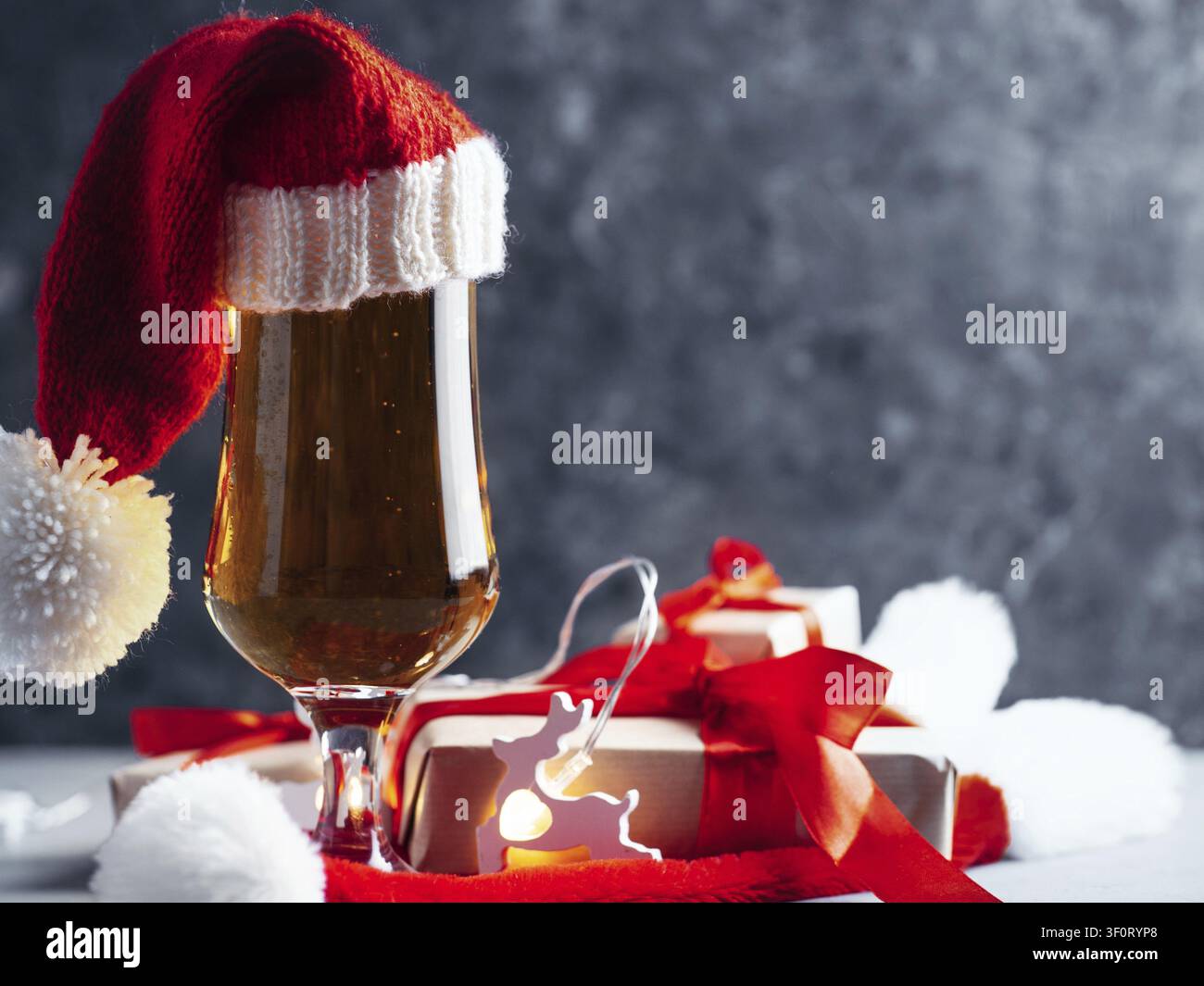 Bicchiere di birra natalizio festoso con cappello di Babbo Natale su sfondo scuro con spazio per il testo Foto Stock