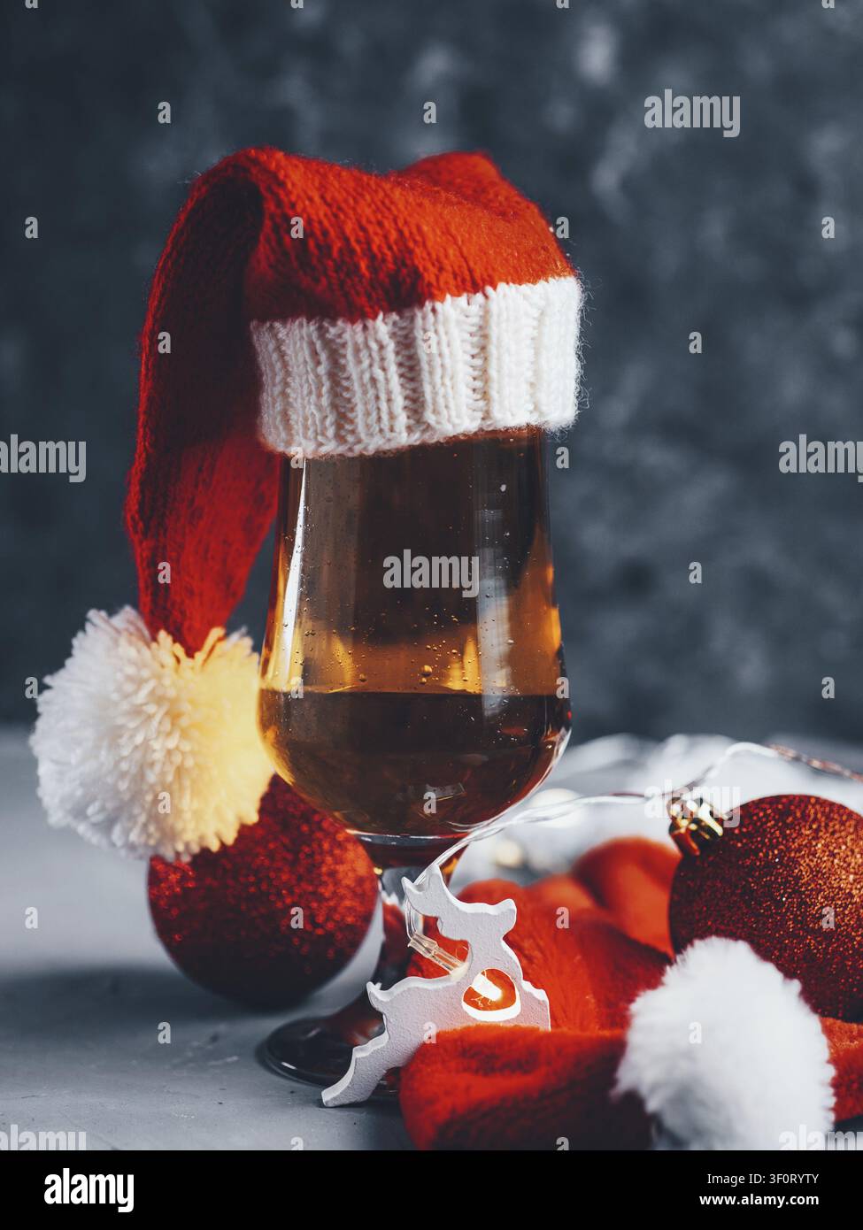 Bicchiere di birra natalizio festoso con cappello di Babbo Natale su sfondo scuro Foto Stock