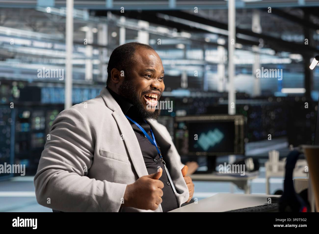 Programmatore entusiasta in una struttura di server soddisfatto dalle metriche di efficienza del sistema migliorate. Uomo afroamericano estatico che lavora in una struttura di server soddisfatto dalle prestazioni migliorate dell'infrastruttura di rete. Foto Stock