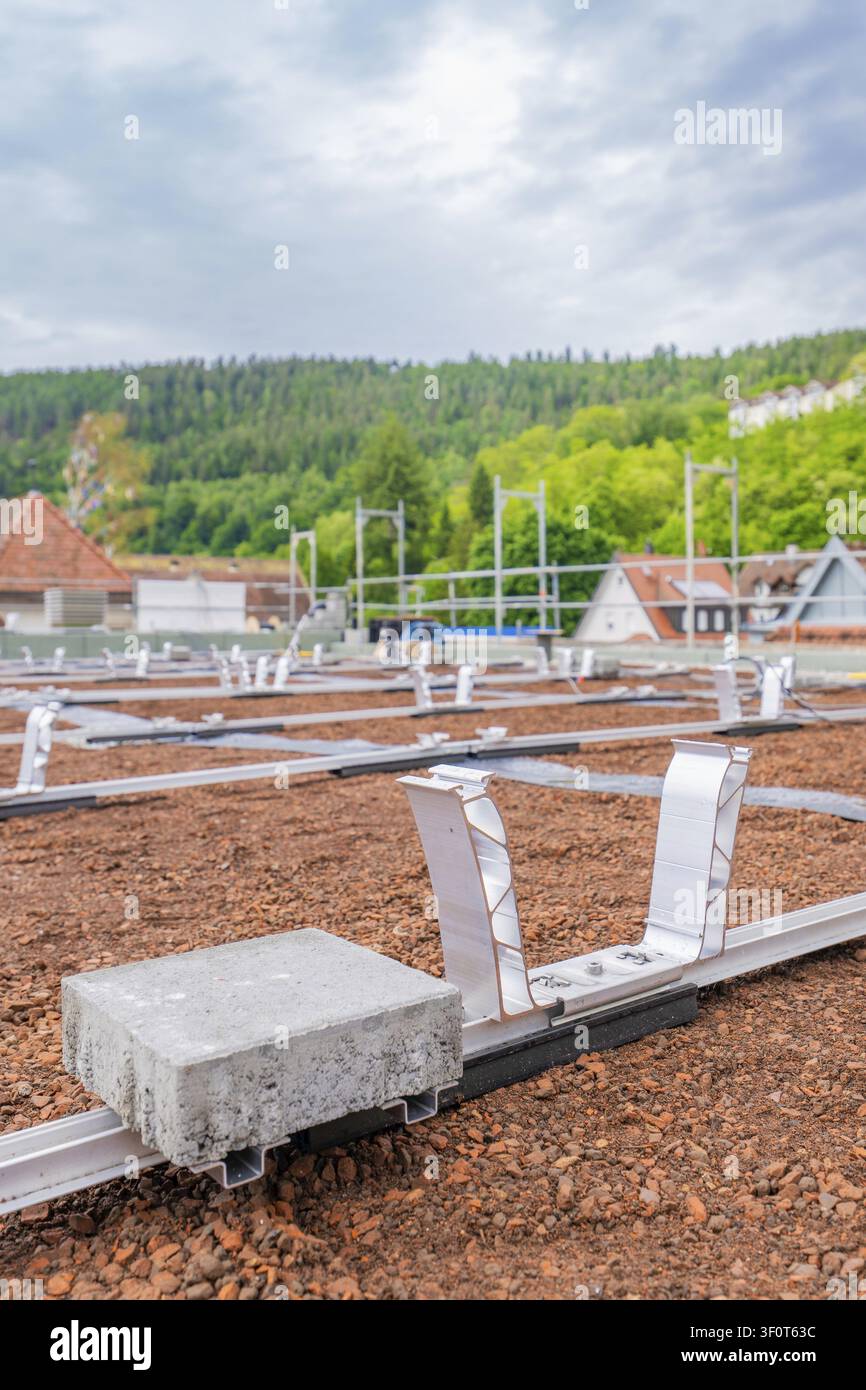 Tetto con binari di montaggio e peso in mattoni su un paesaggio montano nello sfondo, sottostruttura PV, Calw, Germania Foto Stock