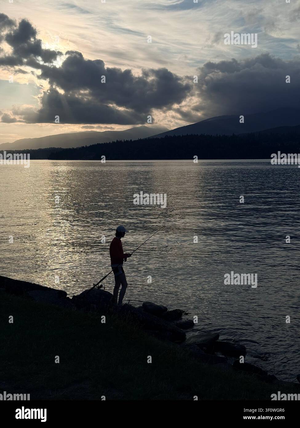 Persona che pesca a Burnaby, British Columbia, Canada: riva e acque calme al Barnet Marine Park alla luce della sera. Foto Stock