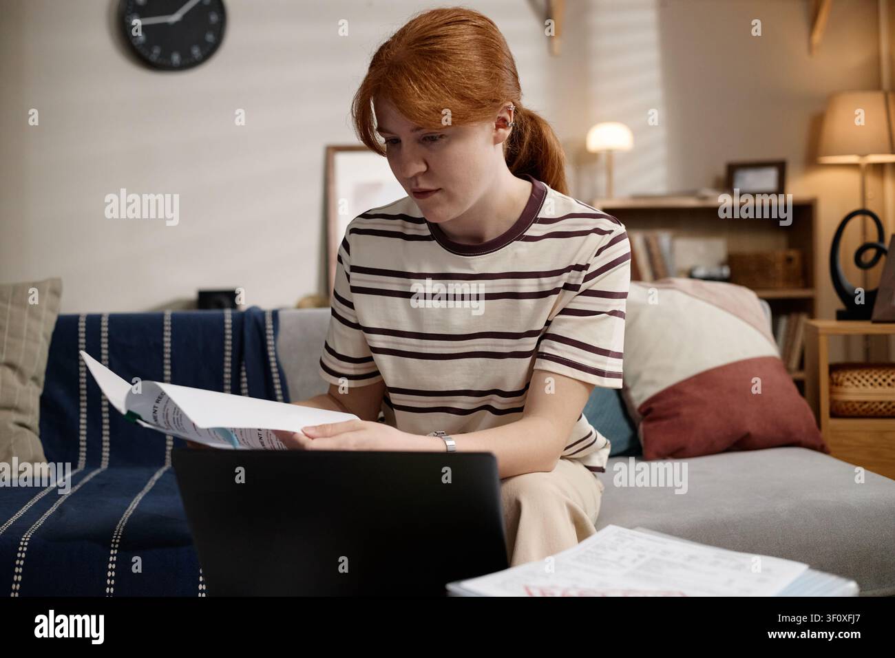 Donna che esamina documenti durante l'apprendimento online a casa Foto Stock