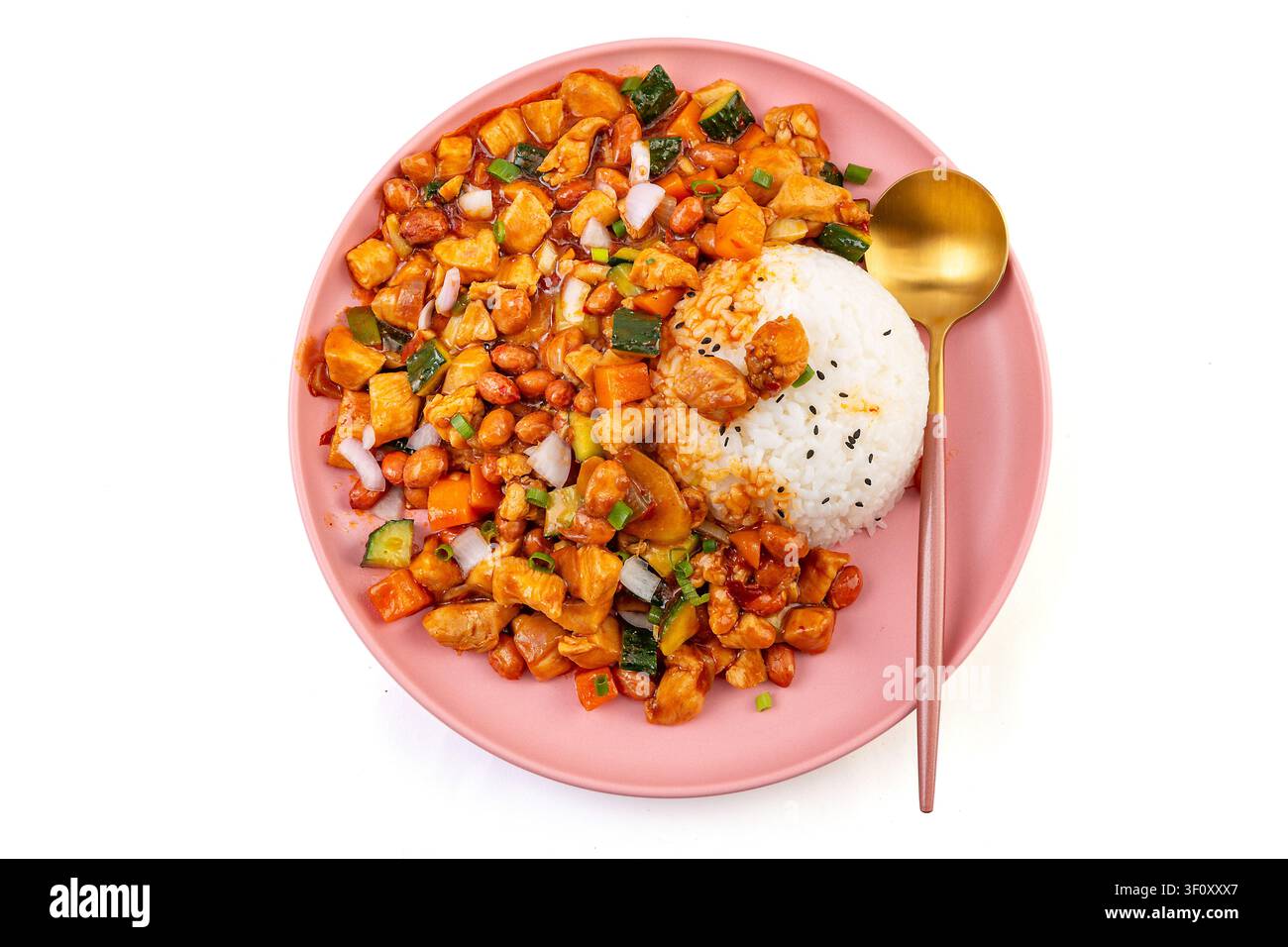 Pollo Kung Pao cinese piccante con arachidi e verdure servito su riso bianco in un piatto rosa. Foto Stock