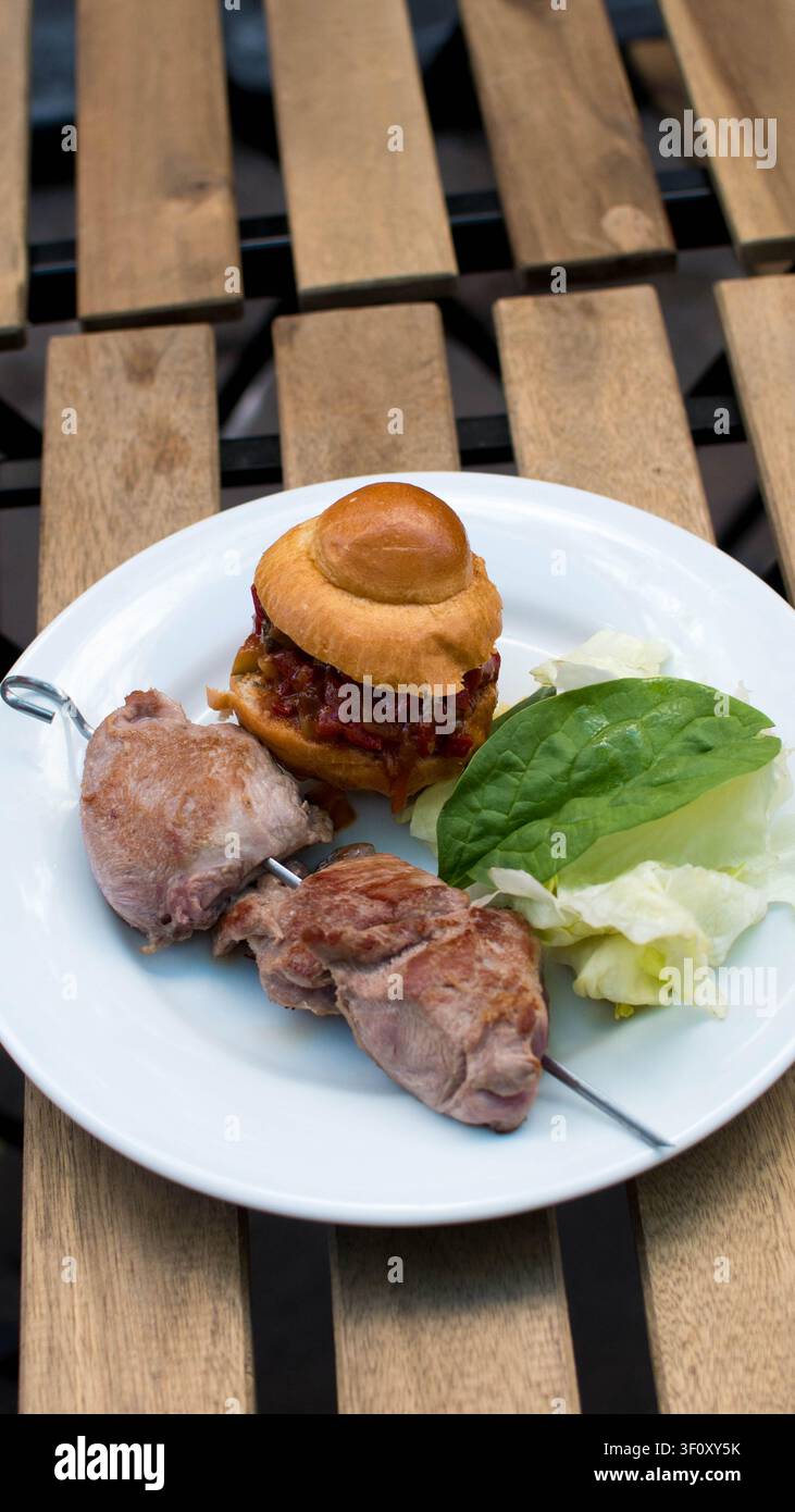 Burger gourmet servito con carne affettata e insalata fresca Foto Stock