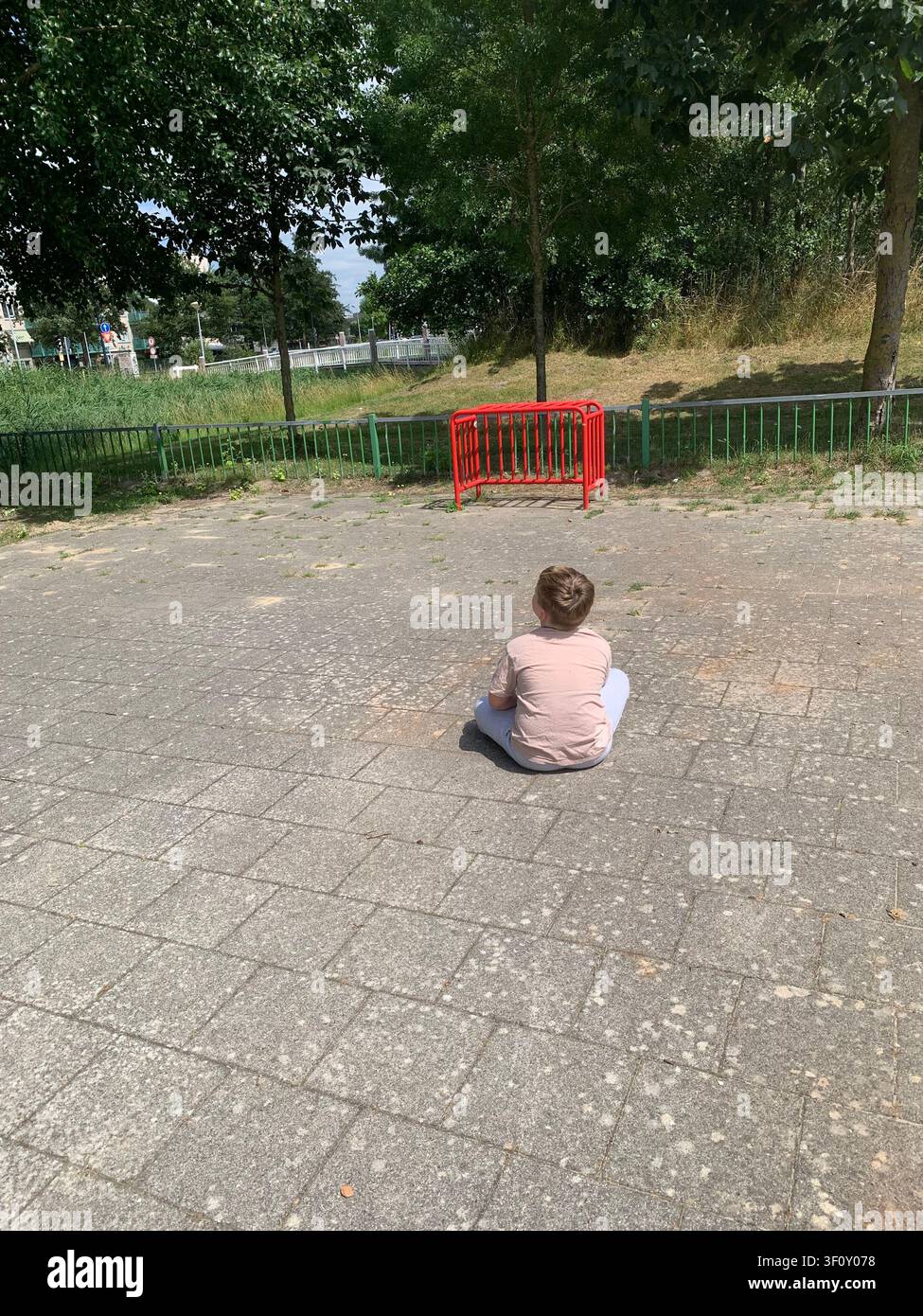 Un ragazzo è seduto da solo al parco giochi. - Immagine stock catturata con smartphone