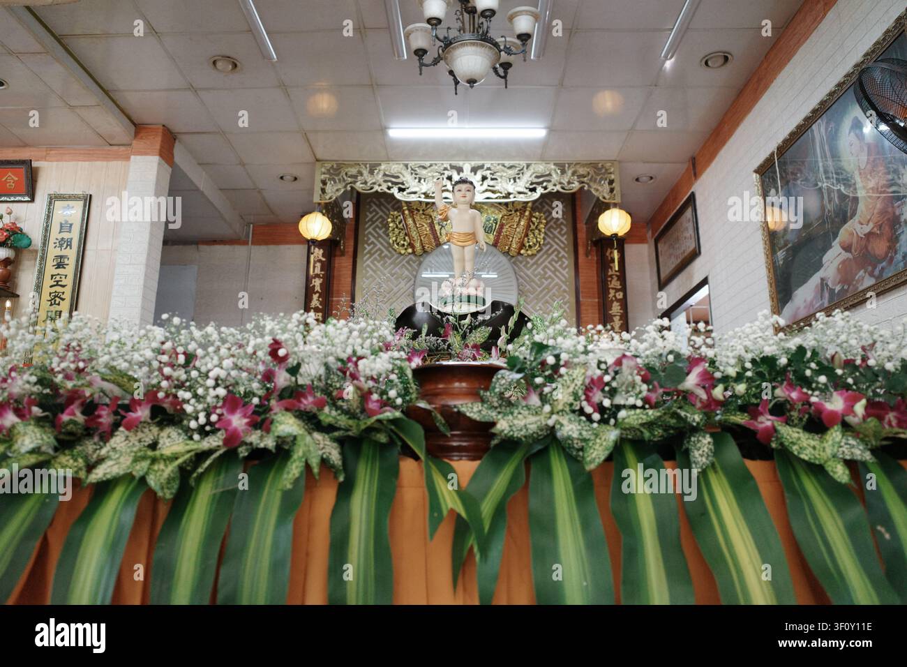 Un altare in legno splendidamente realizzato adornato con fiori vivaci, che crea un'atmosfera serena e invitante. Foto Stock