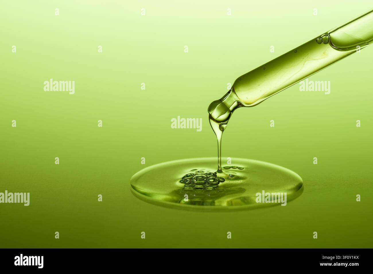 Gocciolatore con una goccia di siero o gel cosmetico sparsa su sfondo verde. Foto Stock