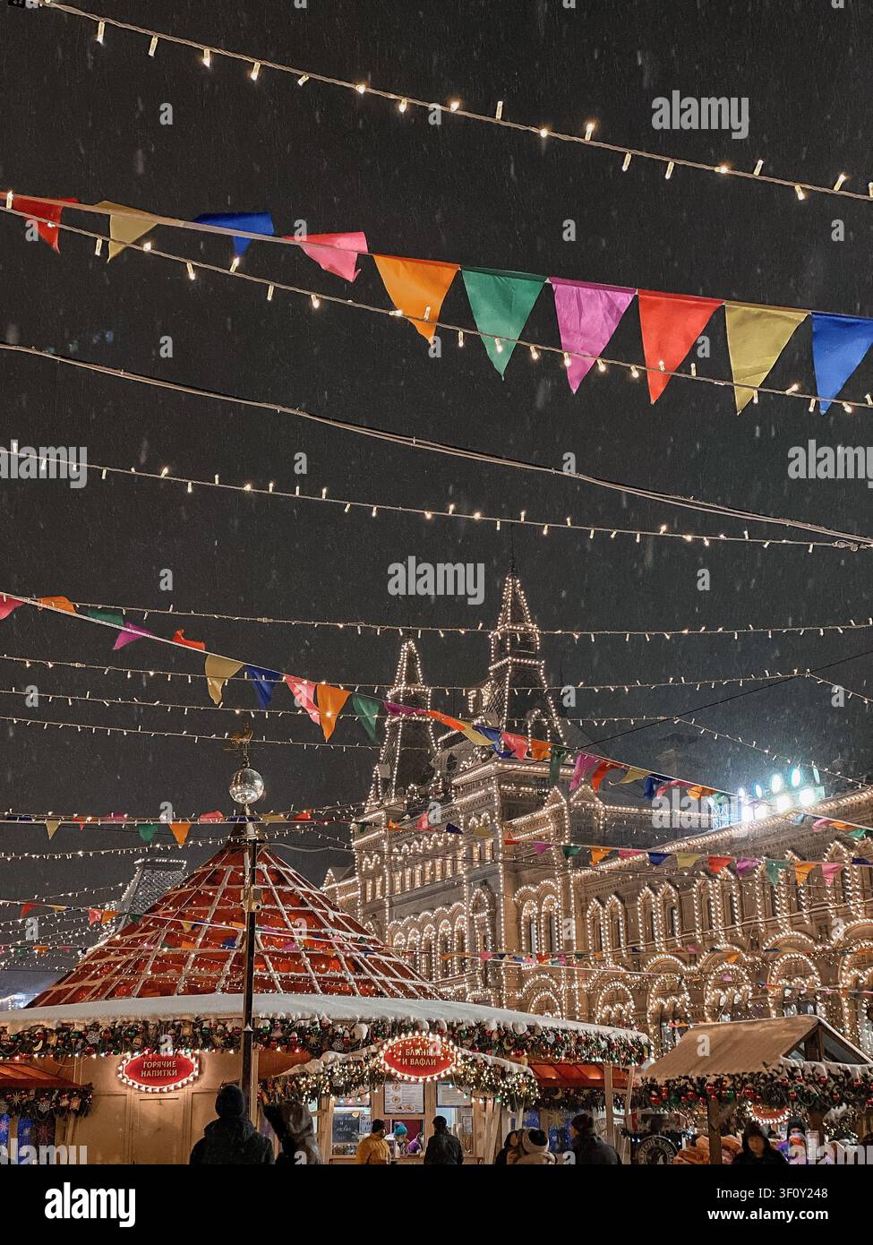 Mosca, Russia - 22 gennaio 2022: Mercato natalizio festivo sotto la nevicata con architettura storica illuminata di notte - Immagine stock catturata con smartphone