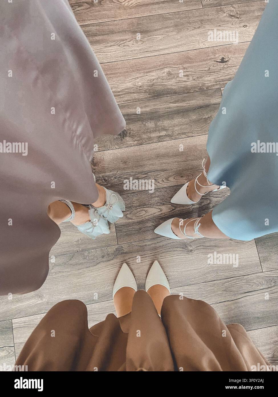 Vista dall'alto di scarpe da donna eleganti e abiti pastello durante una celebrazione indoor alla moda. - Immagine stock catturata con smartphone