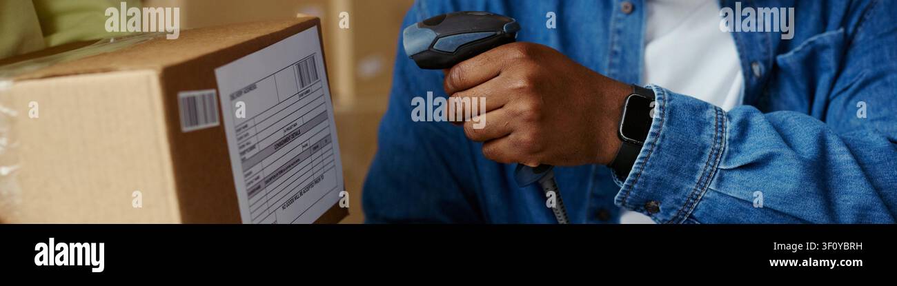 Intestazione di un lavoratore adulto nero che scansiona un'etichetta di spedizione su una scatola di cartone con un lettore di codici a barre, elaborando un pacco per l'adempimento dell'ordine. Ideale per il marketing logistico dell'e-commerce Foto Stock