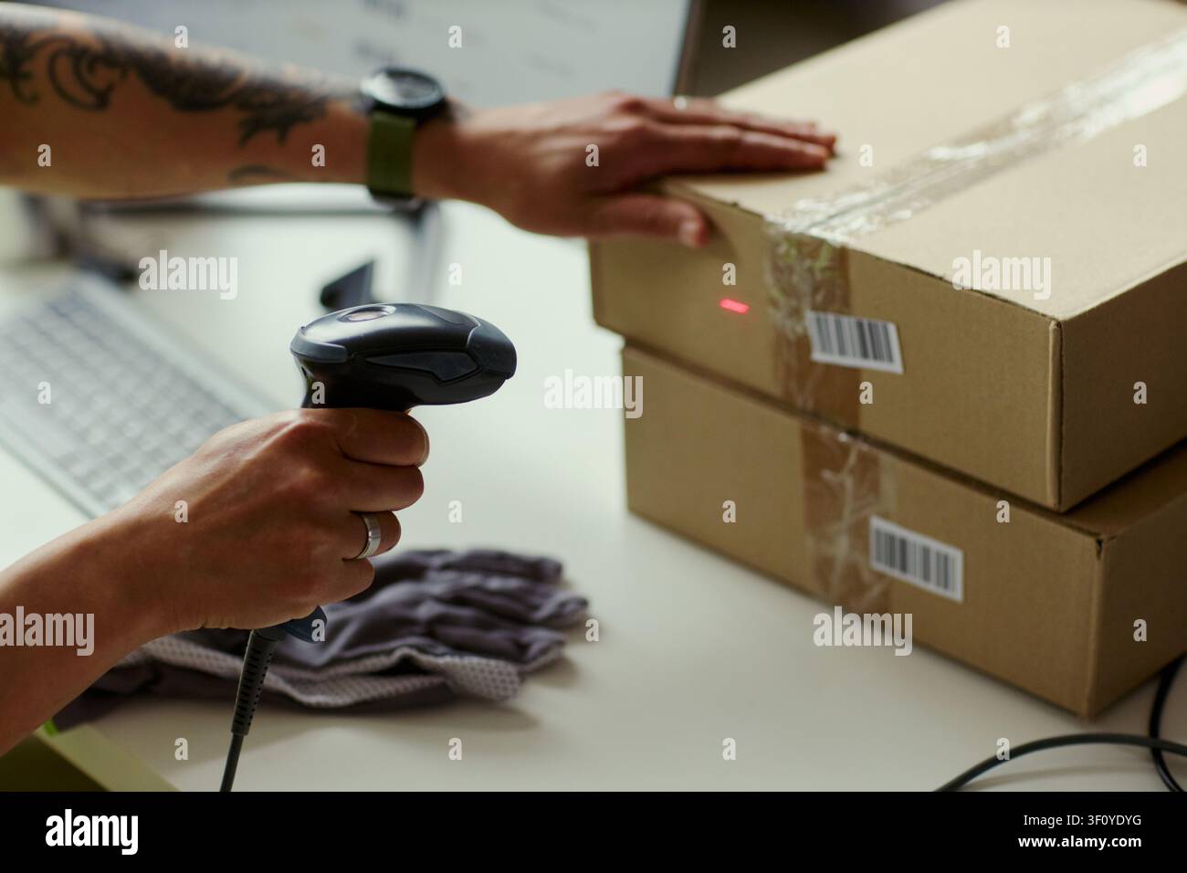 Close up di un giovane lavoratore adulto che scansiona un codice a barre su scatole di spedizione e elabora l'adempimento degli ordini alla stazione di imballaggio. Ideale per la logistica e-commerce, l'inventario, la vendita al dettaglio Foto Stock