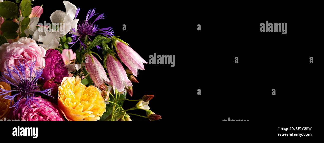 Colorata disposizione floreale su sfondo nero: Rose, gigli e fiori selvatici in contrasto incredibile Foto Stock