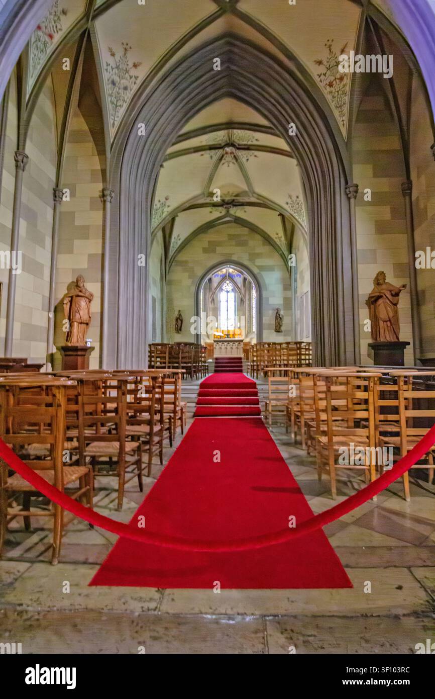 Interno simmetrico di cappella gotica al castello di Hohenzollern con archi di pietra appuntiti, finestre con vetrate colorate e un tappeto rosso che conduce all'historico a Foto Stock