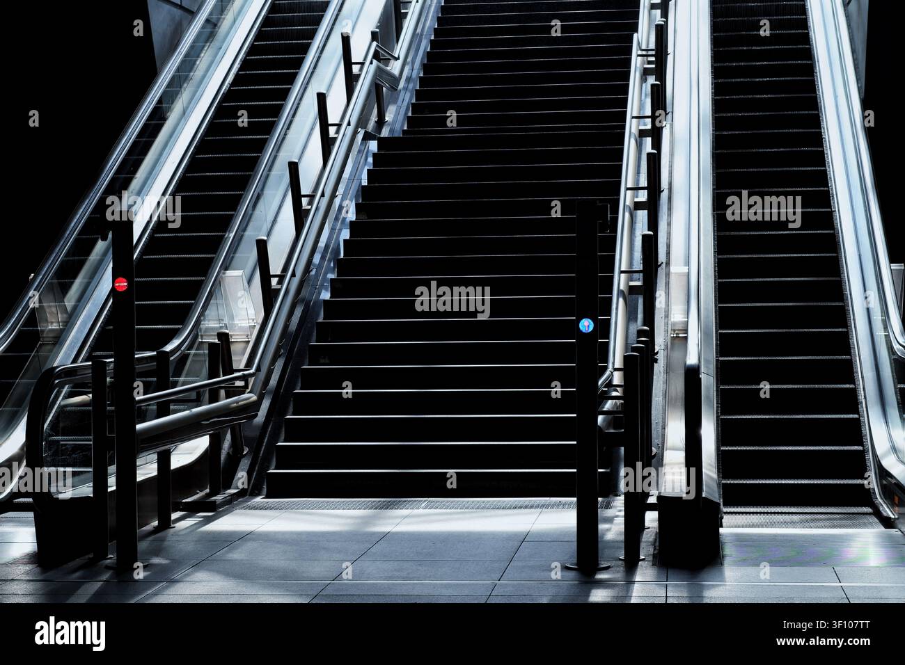Scale mobili simmetriche e scala centrale in un interno architettonico moderno Foto Stock