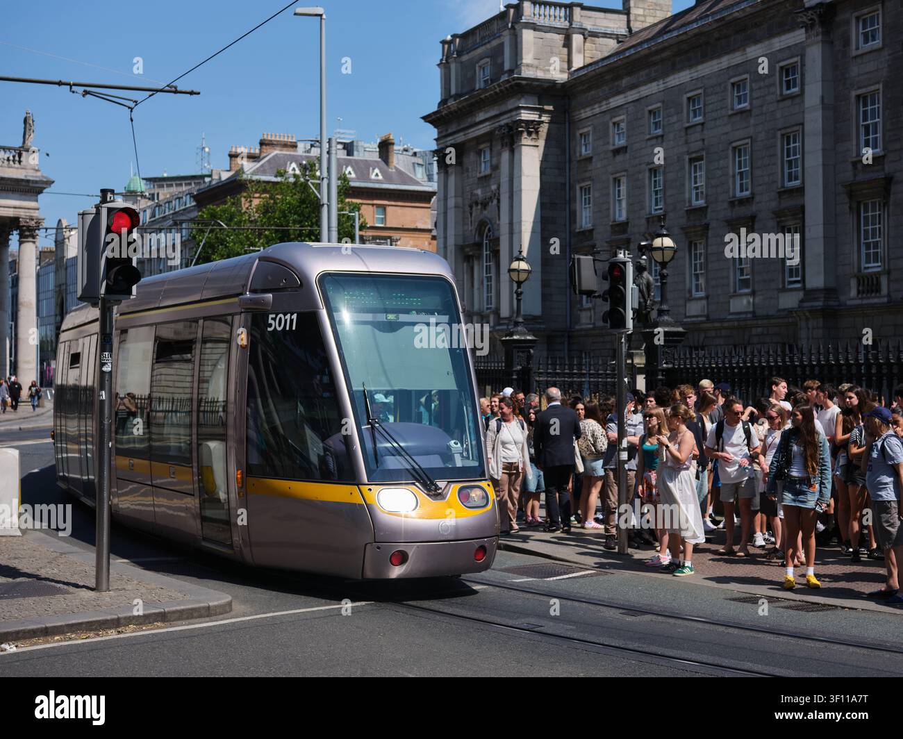 Un tram LUAS che passa davanti al Trinity College nella città di Dublino, Irlanda. Foto Stock