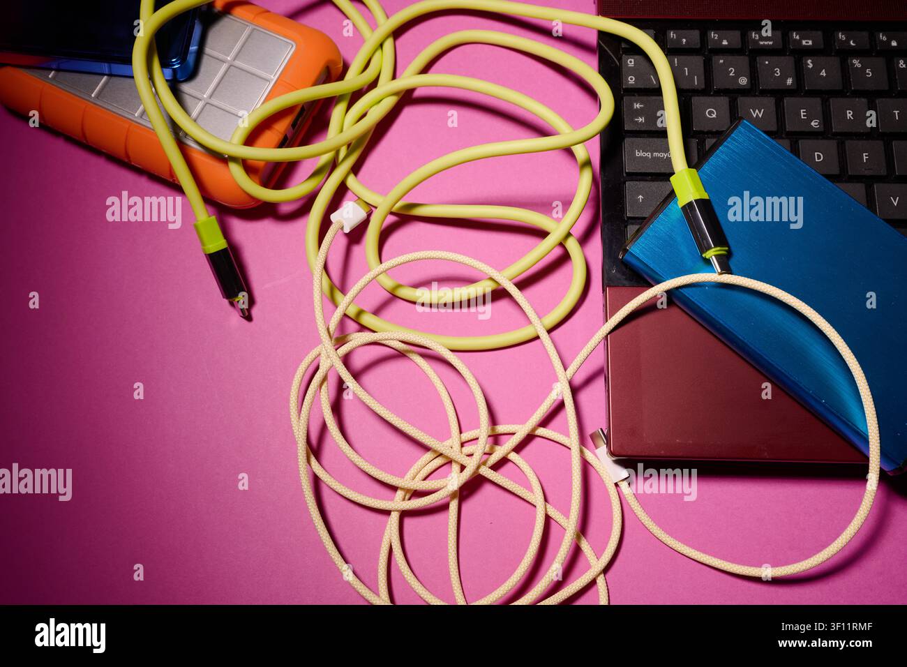 Laptop, disco rigido esterno e cavi di ricarica e trasferimento dati su una scrivania. Archiviazione, trasferimento e backup di informazioni e dati su un dispositivo portatile e Foto Stock