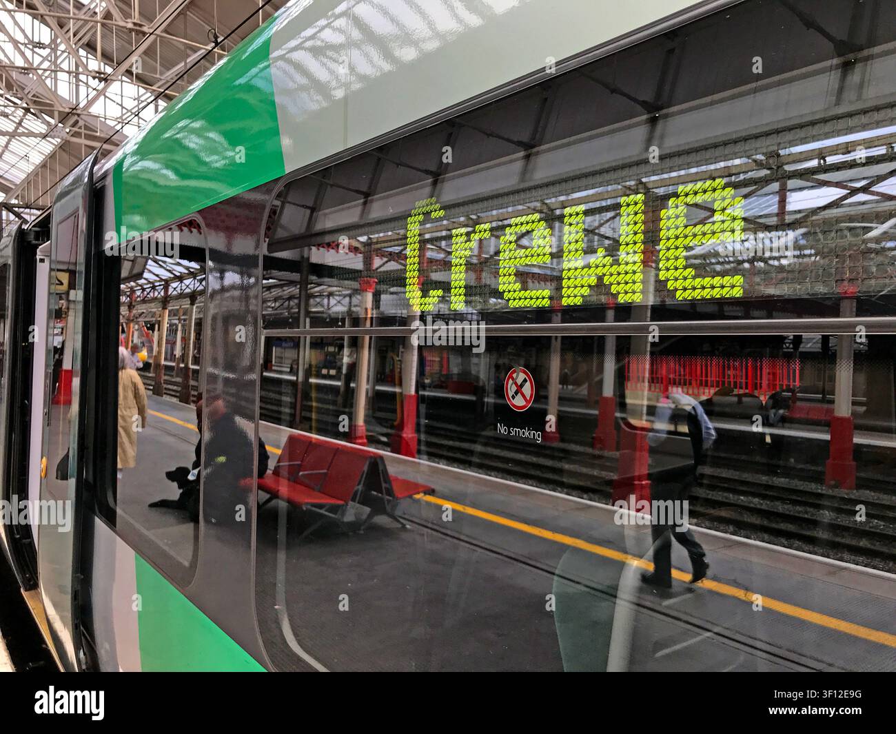 Segnale elettronico di destinazione Crewe e riflessi del binario nella finestra di un treno passeggeri allo snodo ferroviario del Cheshire Foto Stock
