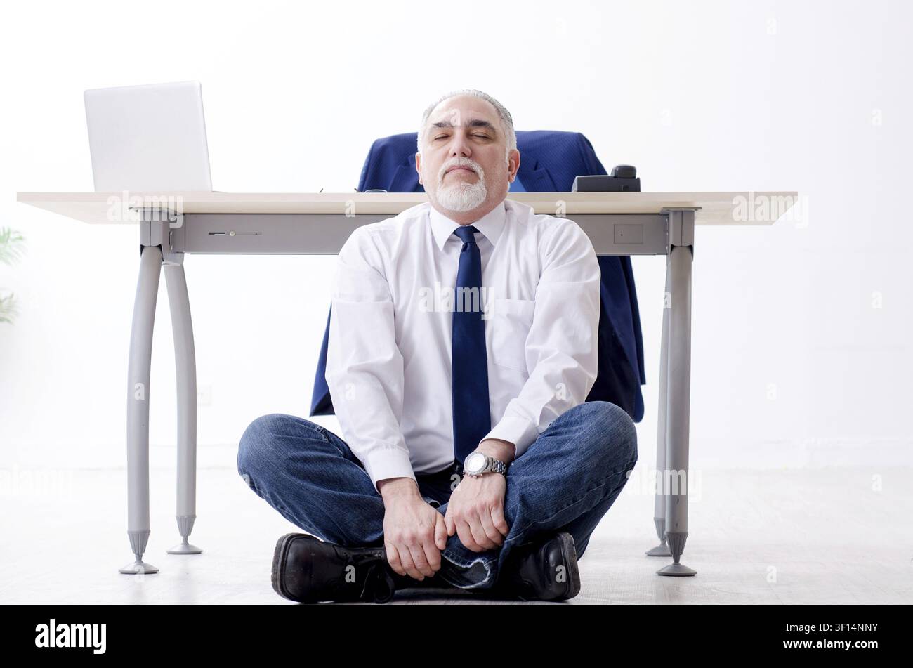 Imprenditore invecchiato facendo esercizi yoga in ufficio Foto Stock