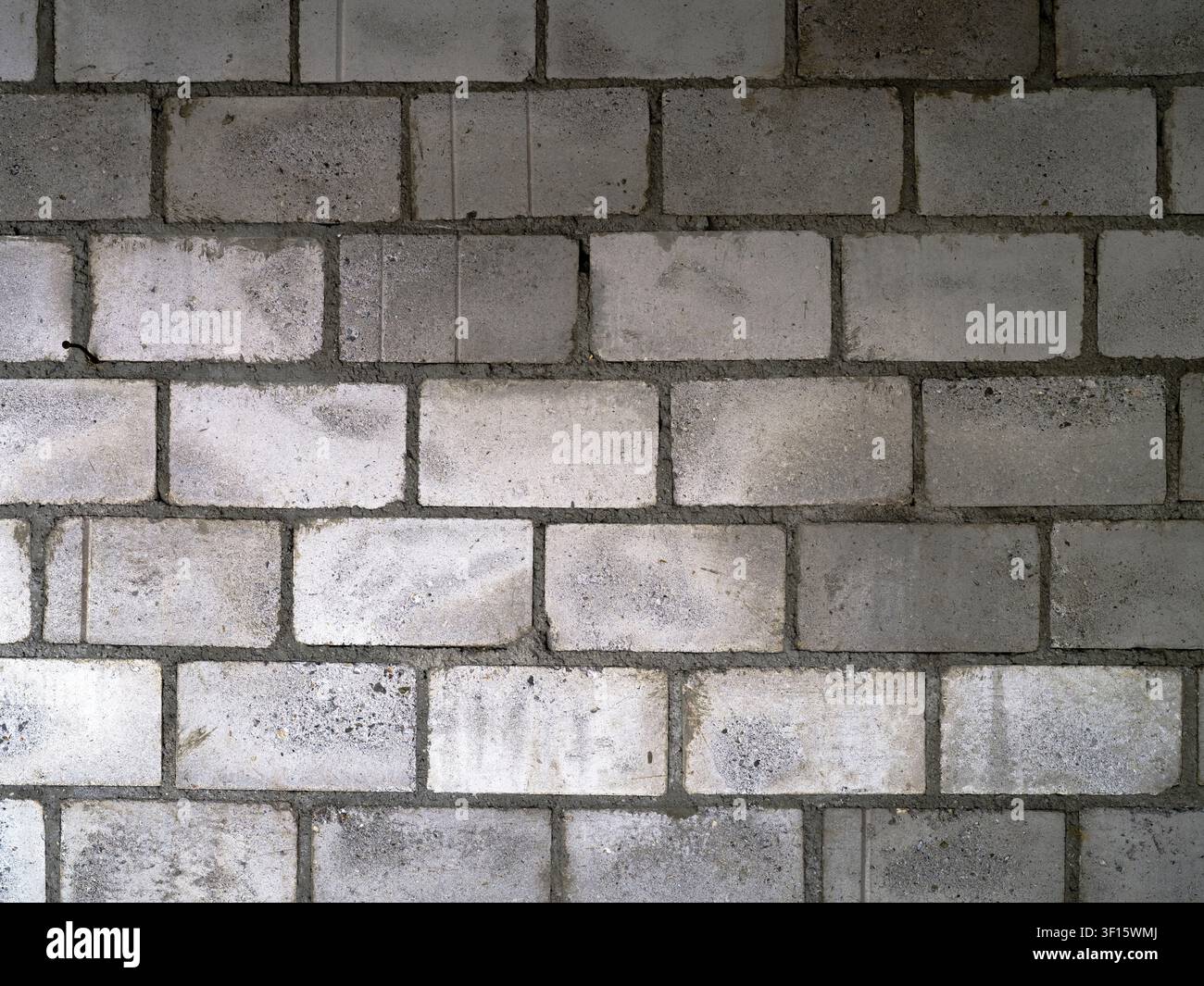 Muro di blocchi di cemento grigio che mostra variazioni di texture e tonalità Foto Stock
