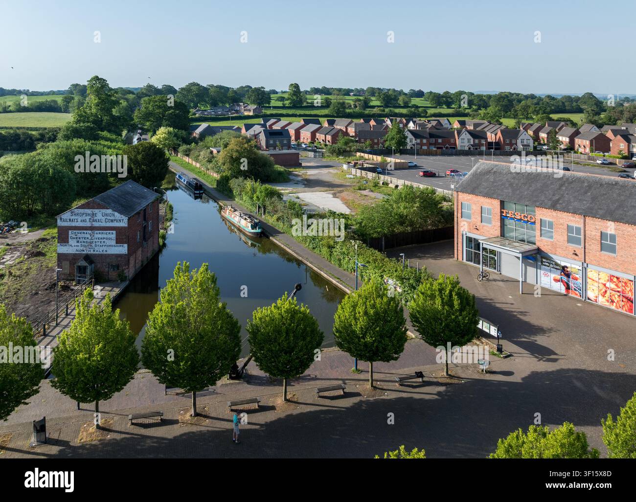 Ellesmere, UK - 25 maggio 2026: Veduta aerea che cattura il tranquillo canale di Llangollen, un magazzino storico e il moderno negozio Tesco a Ellesmere, Shropshire. Foto Stock