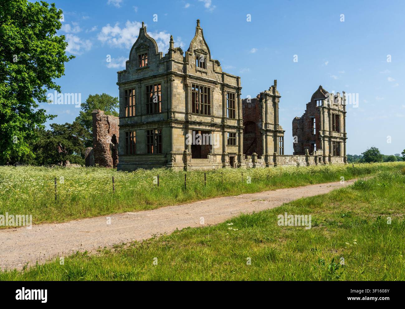 Rovine di un castello storico inglese, con architettura intricata e muratura fatiscente contro un cielo blu brillante. Foto Stock