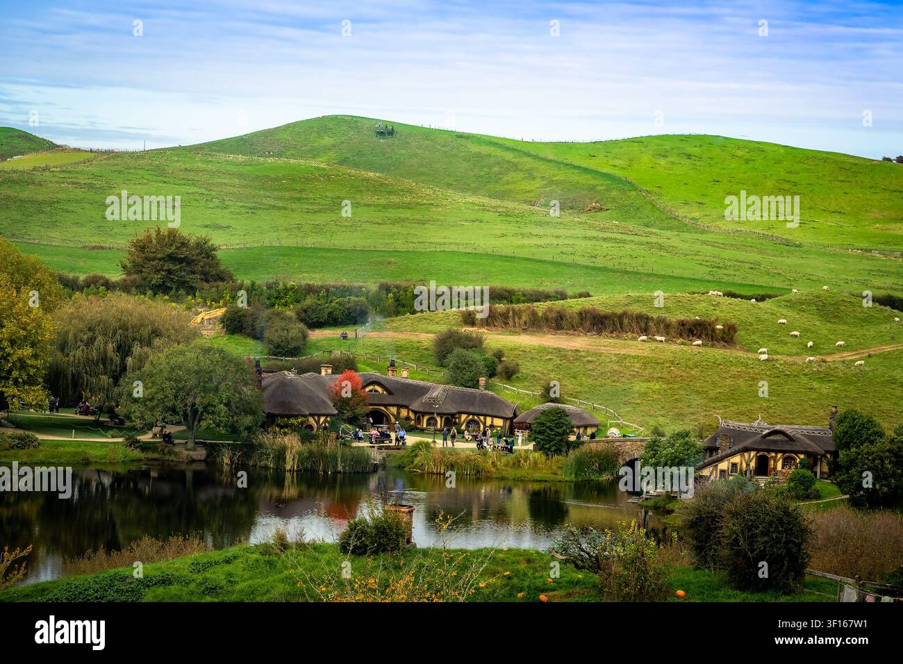 Vista panoramica scenografica dell'iconico Green Dragon Inn e delle case Hobbit al set cinematografico di Hobbiton, circondati da rigogliose colline verdi e un tranquillo Foto Stock