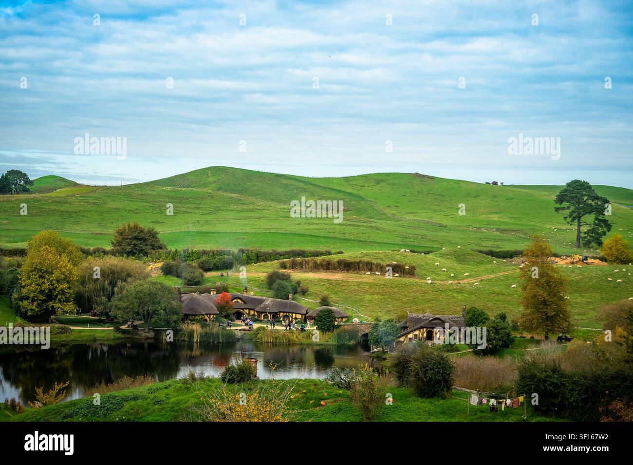 Vista panoramica scenografica dell'iconico Green Dragon Inn e delle case Hobbit al set cinematografico di Hobbiton, circondati da rigogliose colline verdi e un tranquillo Foto Stock