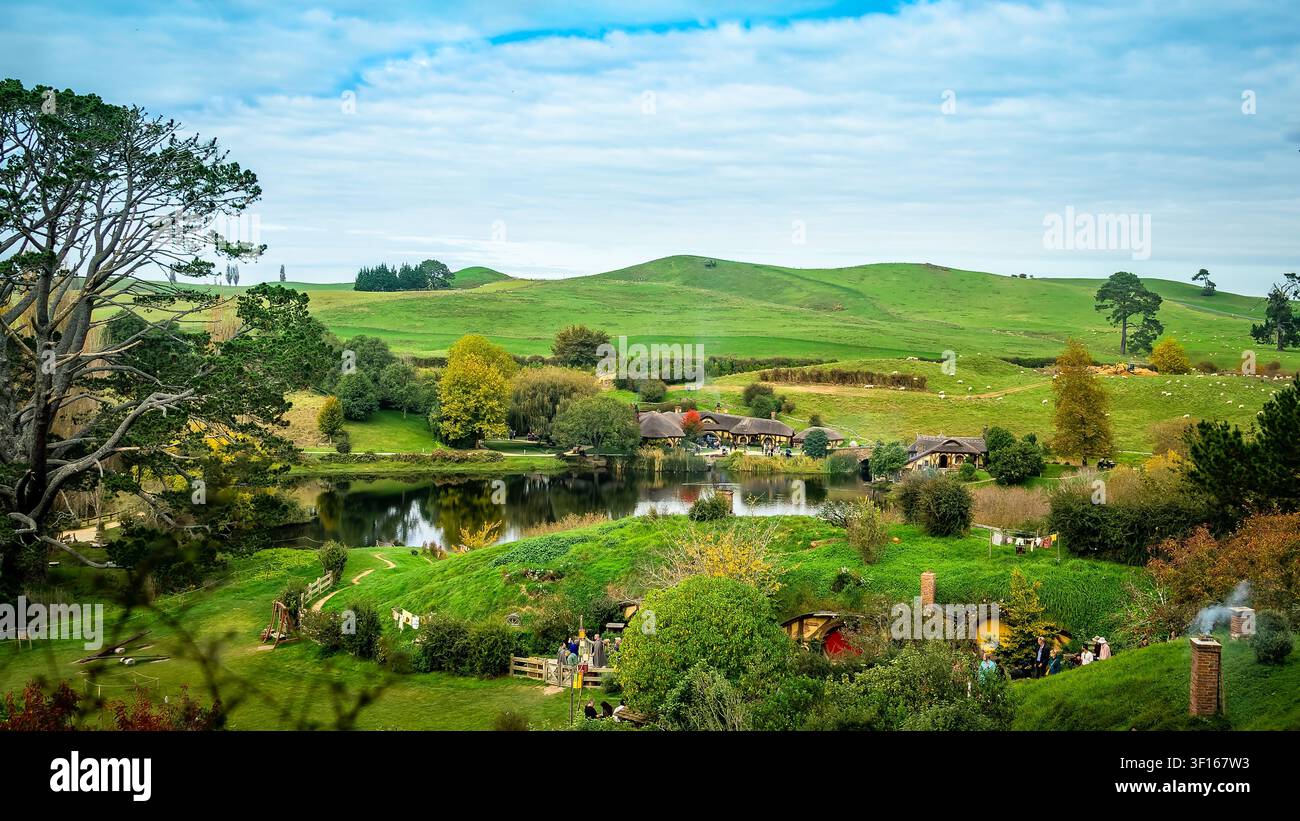 Vista panoramica scenografica dell'iconico Green Dragon Inn e delle case Hobbit al set cinematografico di Hobbiton, circondati da rigogliose colline verdi e un tranquillo Foto Stock