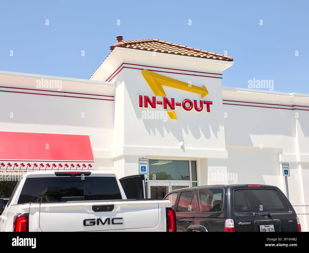 DALLAS, TX, USA - 10 LUGLIO 2026: L'esterno di un ristorante In-N-Out Burger mostra il suo iconico logo rosso e giallo sotto un cielo azzurro. In-N-Ou Foto Stock