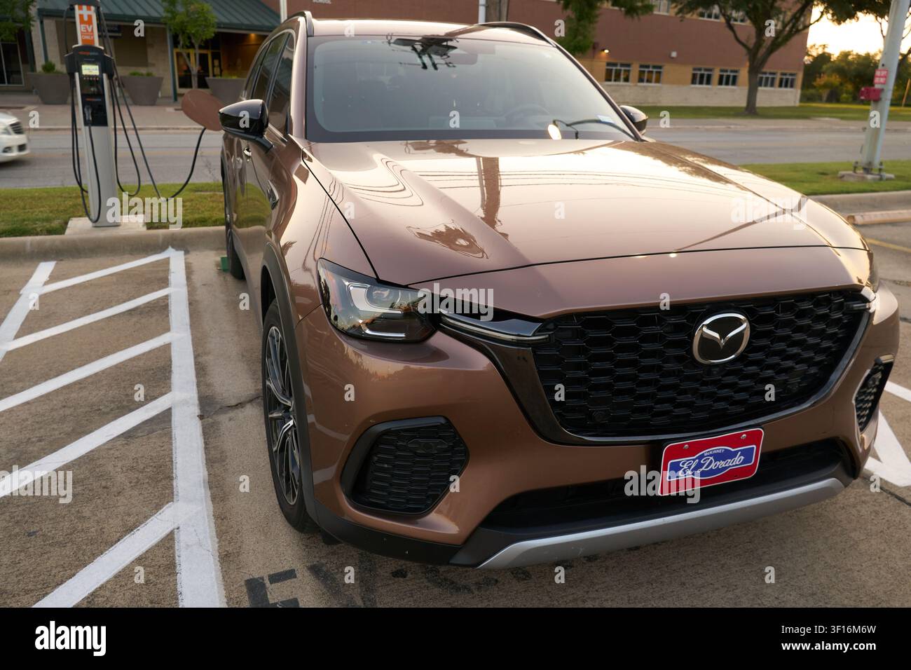 FARMERS BRANCH, TX, USA - 10 LUGLIO 2026: Una Mazda CX-70 PHEV in Melting Copper Metallic è parcheggiata a una stazione di ricarica. Questo veicolo ibrido plug-in elettrico Foto Stock