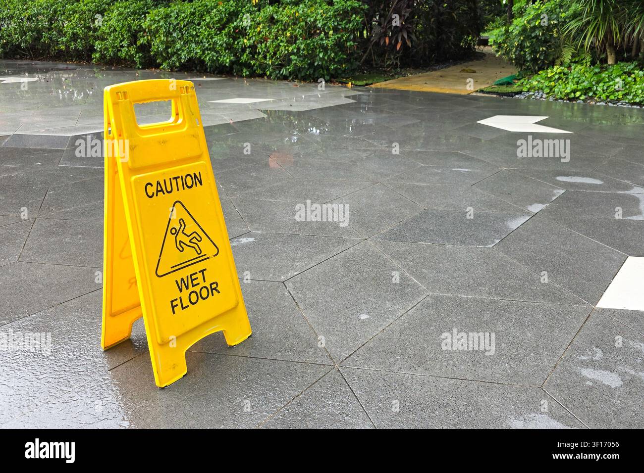 Cono "Attenzione pavimento bagnato" in colore giallo accattivante esposto all'aperto dopo la pioggia come avvertimento per i pedoni Foto Stock