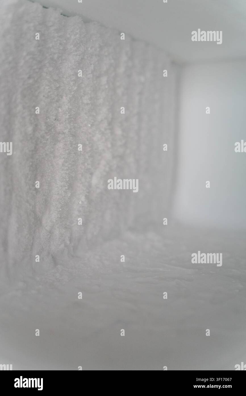 Gelo spesso all'interno di un congelatore domestico causato da scongelamento trascurato. L'accumulo di ghiaccio aumenta il consumo di energia e gli costi elettrici domestici Foto Stock