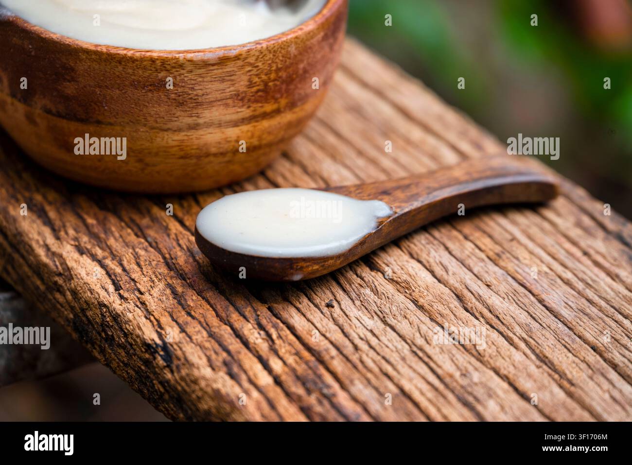 Ghee o burro chiarificato in una ciotola di legno, olio da cucina, ghee puro su sfondo di legno Foto Stock