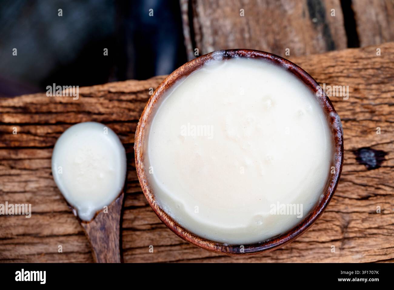 Ghee o burro chiarificato in una ciotola di legno, olio da cucina, ghee puro su sfondo di legno Foto Stock