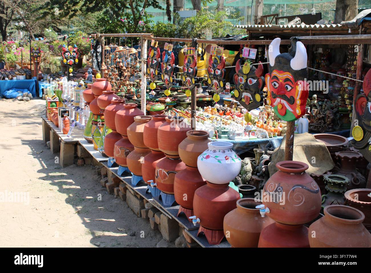 Una colorata esposizione all'aperto di ceramica tradizionale indiana, anfore con rubinetti e maschere decorative di demoni (Mahakala o Mahachanda) su un lato della strada Foto Stock