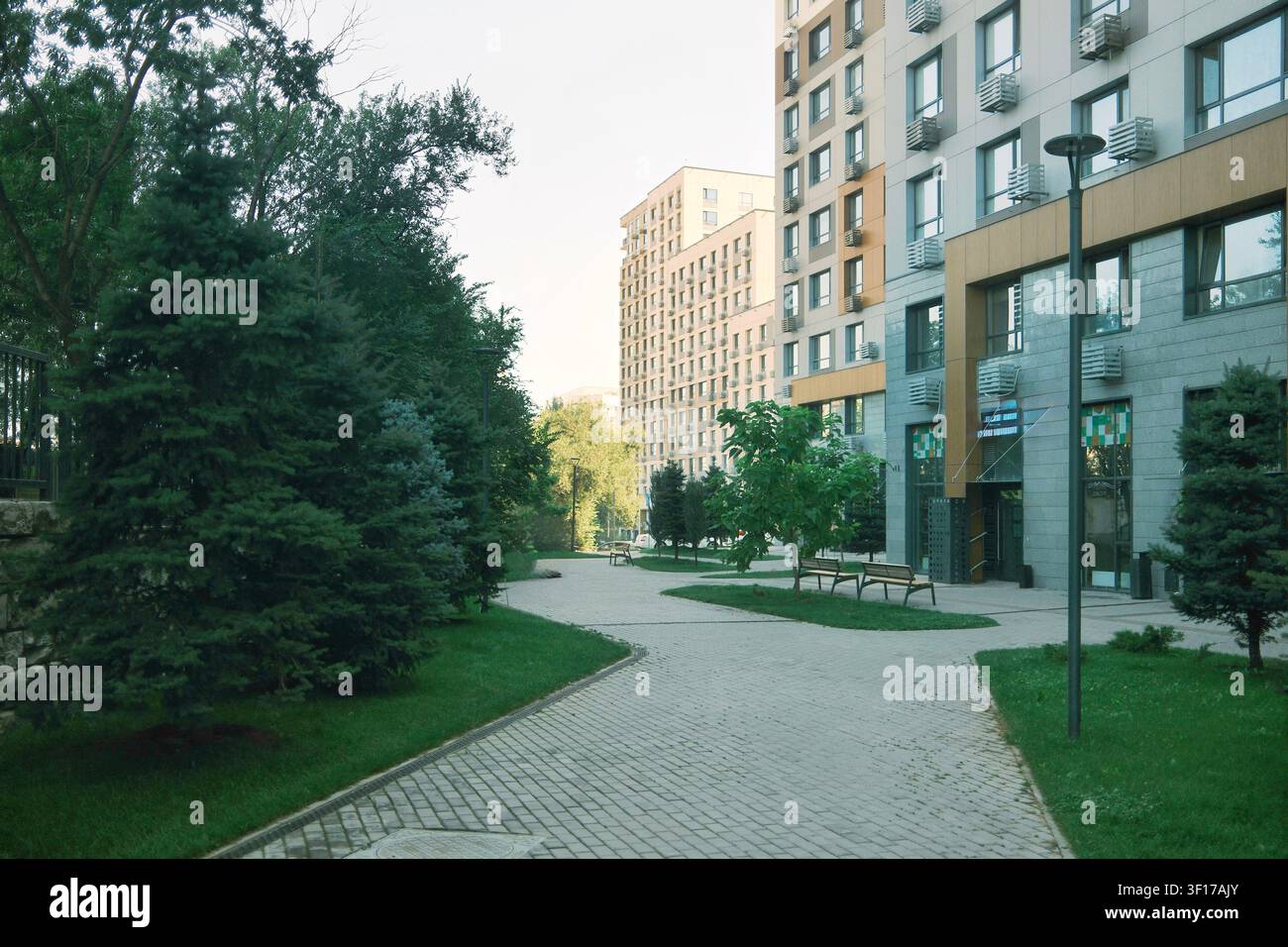 Bellissimo cortile paesaggistico tra moderni edifici residenziali con percorsi pedonali, alberi e spazi verdi in un quartiere contemporaneo Foto Stock
